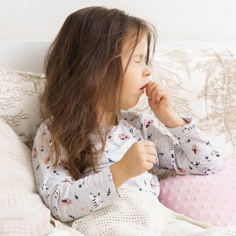Niña en la cama, afectada por la tos